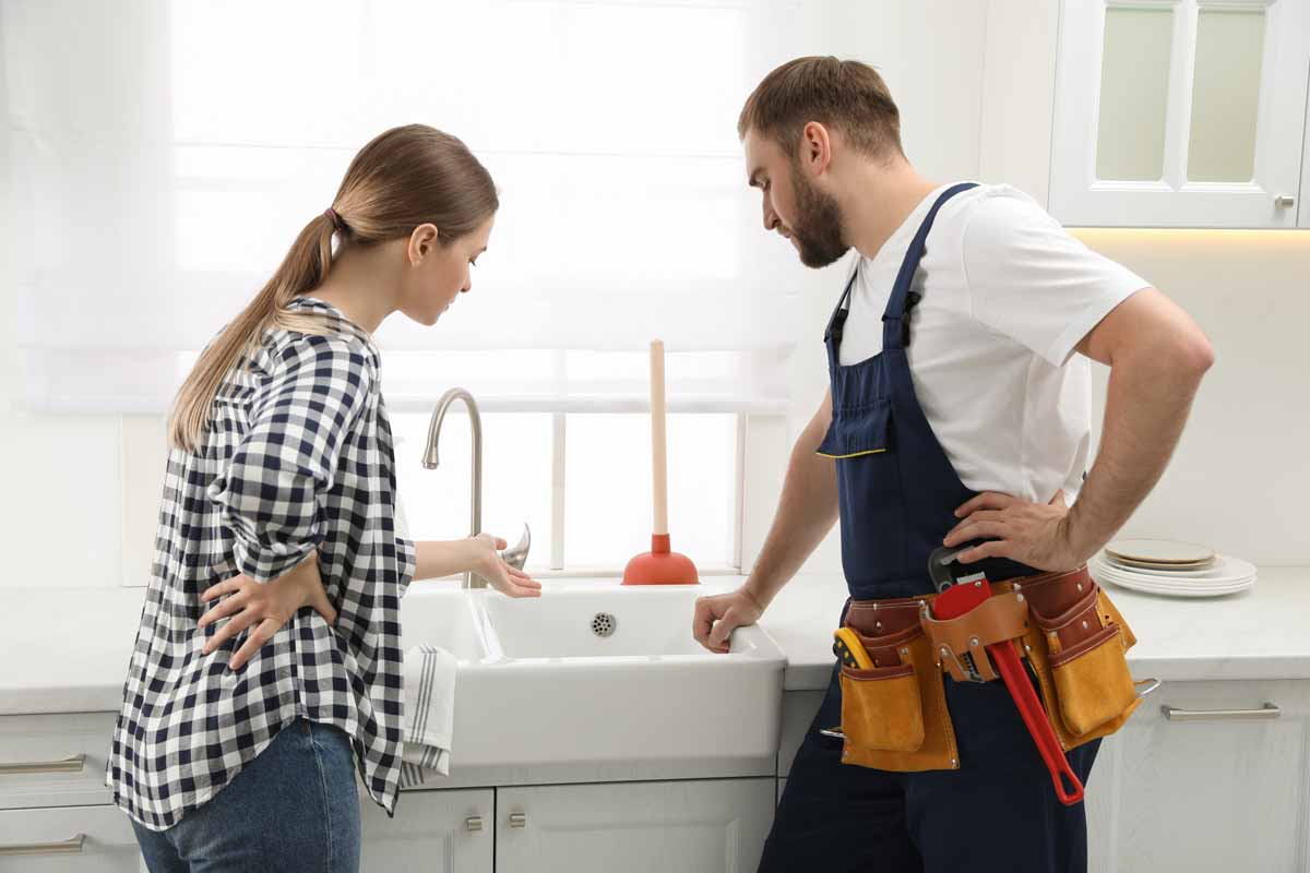 Plumber and homeowner talking and inspecting a kitchen sink